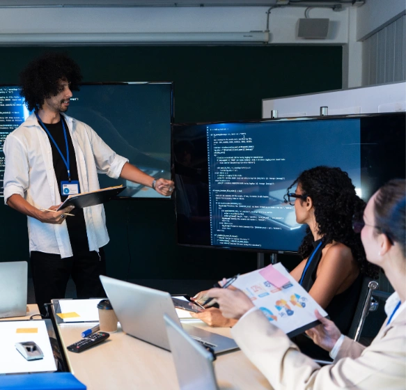 Two senior backend engineers reviewing API code together on a monitor