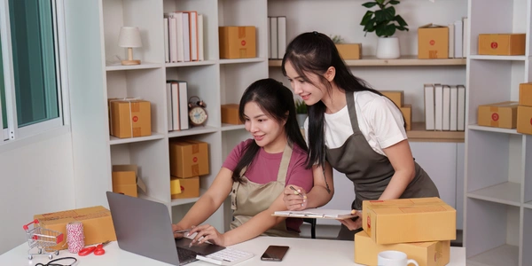 Small business owner launching an online store beside shipping boxes
